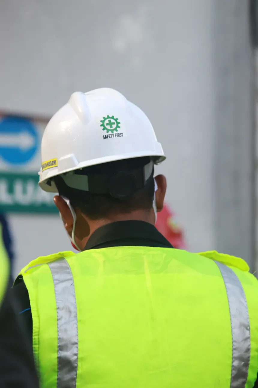 Ouvrier de dos avec casque et gilet haute visibilité — JG Conseil HSE, conseil en prévention des risques